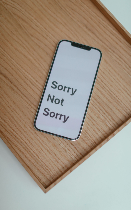 A smartphone displaying the words Sorry Not Sorry on a wooden tray
